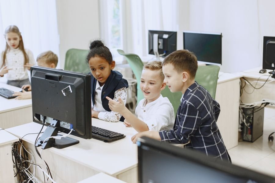 Des enfants découvrent l'informatique autour d'un ordinateur en classe.