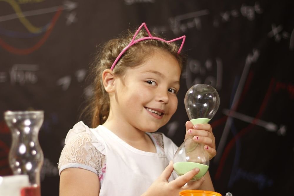 Une petite fille ravie tient un flacon dans son premier labo de sciences.